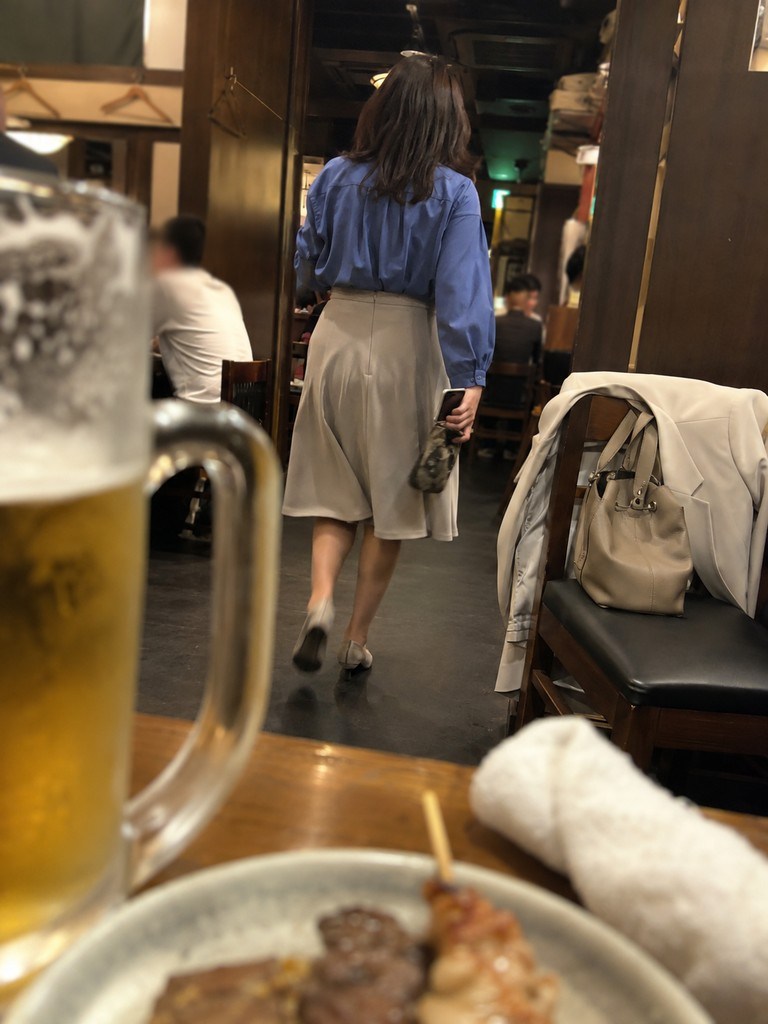 イククルで会ったママが居酒屋で席を立つ後ろ姿、手前にビールと串